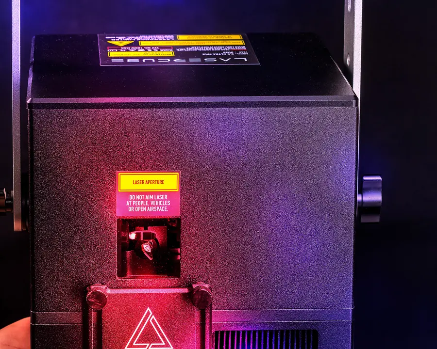Laser aperture of a LaserCube with its yellow warning label
